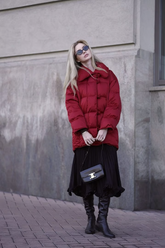 a lady in a red down coat and a black pleated skirt